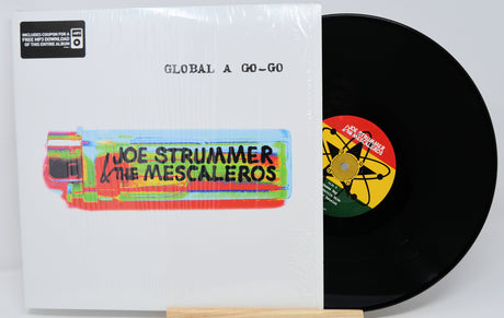 Vinyl record with colorful cover featuring 'Joe Strummer & The Mescaleros' on a white background