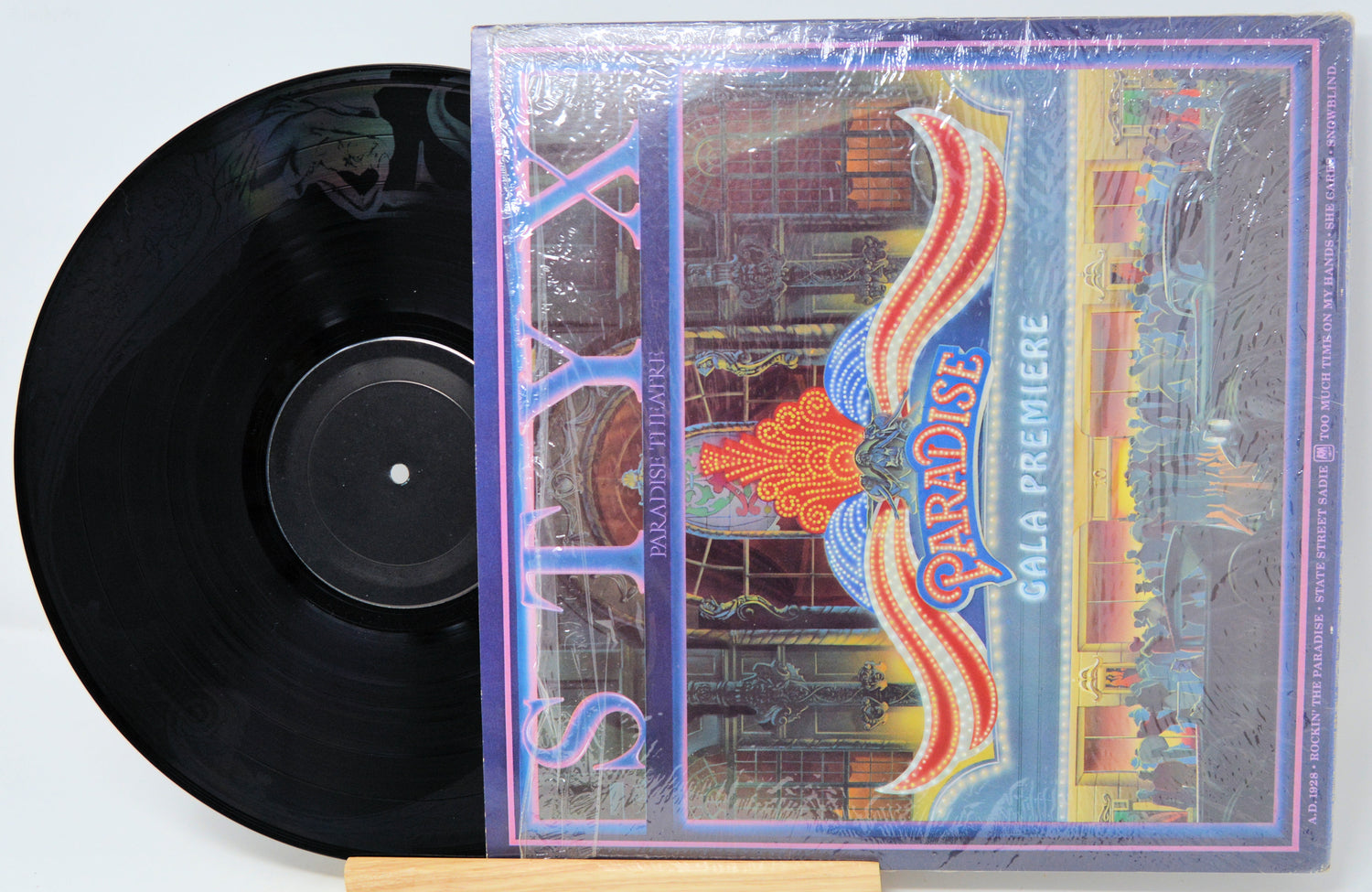 Vinyl record with a colorful cover featuring the word 'Paradise' on a white background