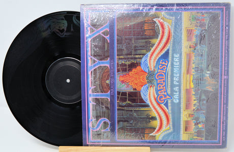 Vinyl record with a colorful cover featuring the word 'Paradise' on a white background