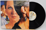 A vinyl record partially pulled from its sleeve, showing the album cover art and the black record disc on a light gray background.