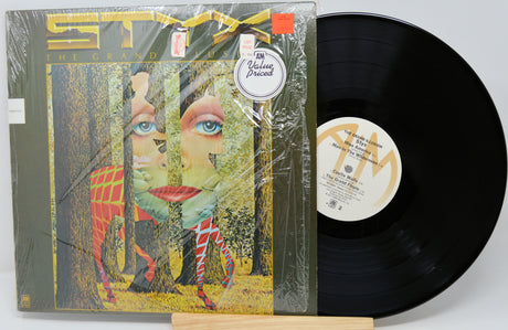 Vinyl record with a colorful cover featuring a face and trees, on a white background.