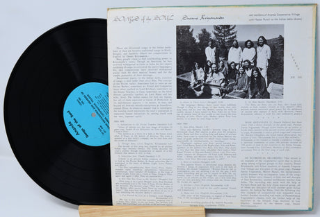 Vinyl record with a blue label and its cover showing text and a black and white photo.