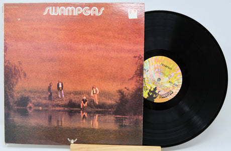 Front cover of Swampgas vinyl LP featuring band by a reflective pond, with bold logo