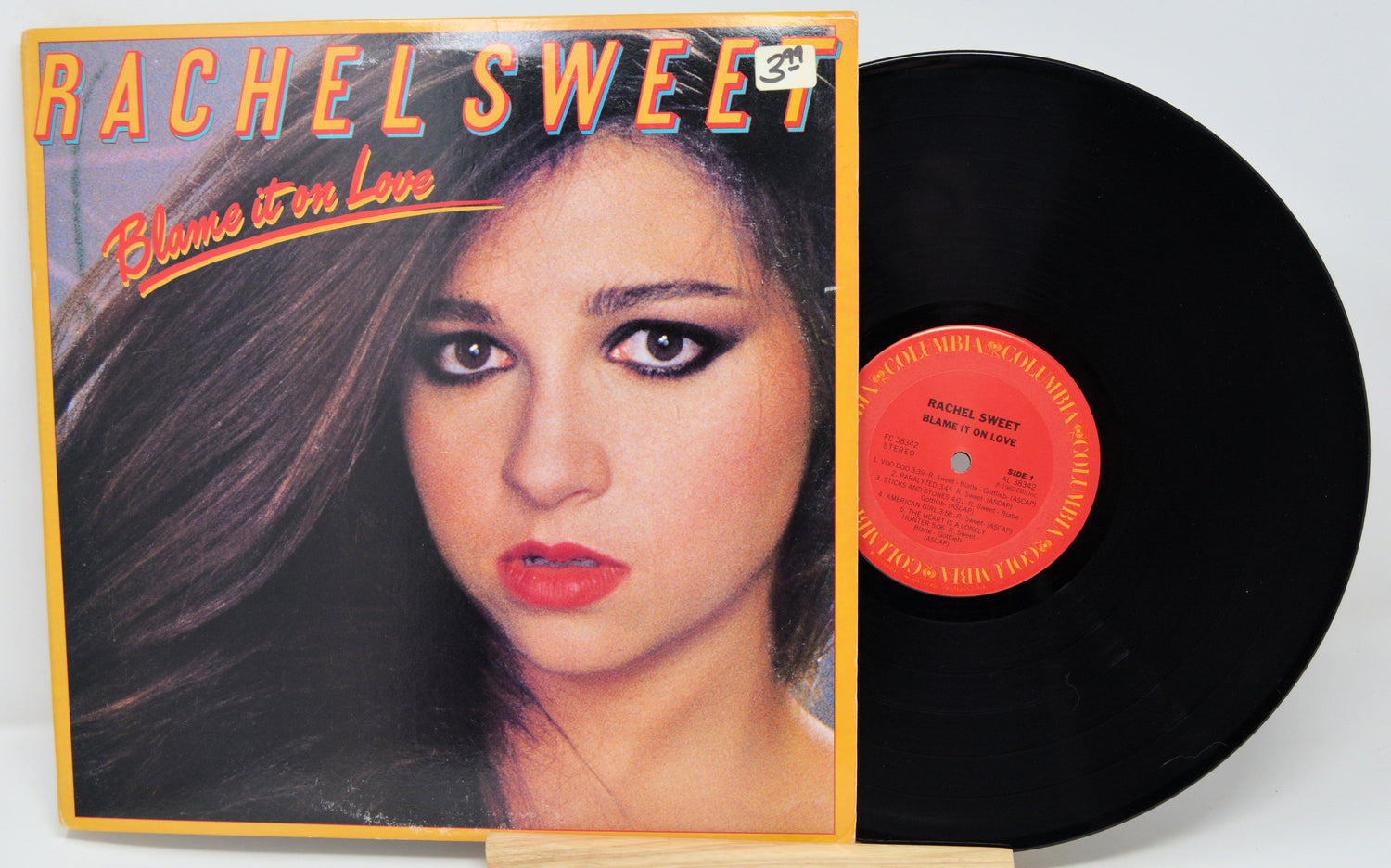 Vinyl record with cover featuring a woman's face and 'Rachel Sweet Blame it on Love' text.