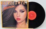 Vinyl record with cover featuring a woman's face and 'Rachel Sweet Blame it on Love' text.