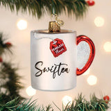 Swiftea mug ornament hanging on a Christmas tree with glowing lights