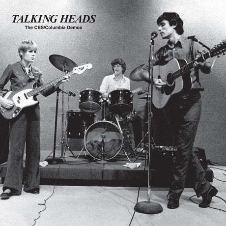 Black and white photo of a band performing on stage with 'Talking Heads' text above.