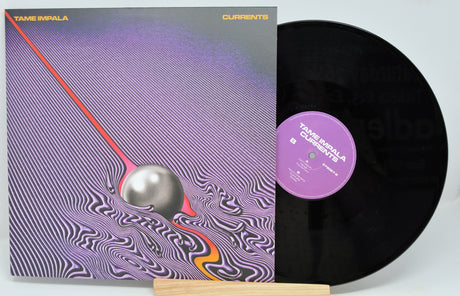 A vinyl record of the album 'Currents' by Tame Impala, featuring a purple and orange album cover with a stylized design.