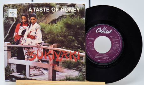 Vinyl record with cover featuring two people and 'A Taste of Honey' text, on a light gray background.