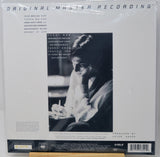 Vinyl record sleeve for Miles Davis' 'Original Master Recording' LP, sealed in plastic shrink wrap. The white cover features a large black-and-white portrait of Davis, tracklist text on the left, and a black label band at the bottom with a barcode.