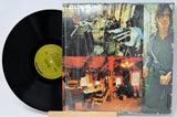 Vinyl record with a colorful cover featuring people in a studio setting.