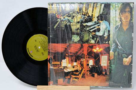 Vinyl record with a colorful cover featuring people in a studio setting.