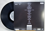 A vinyl record partially pulled from its sleeve, showing the back of the packaging. The black record is visible on the left, and the sleeve is black with white printed tracklist text and the title 'TEARS FOR FEARS' near the bottom.