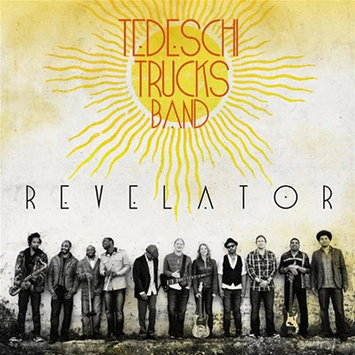 Album cover for 'Revelator' by Tedeschi Trucks Band, featuring a group photo of the band members standing in front of a textured wall, with a large yellow sun graphic and the band's name in red text at the top.