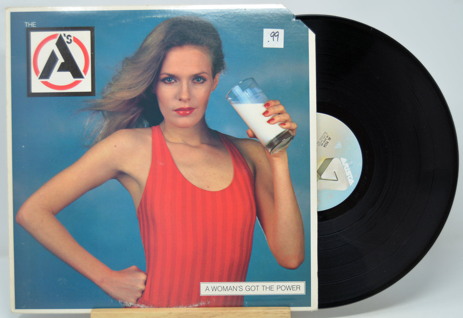 Vinyl record with a cover featuring a woman in a red dress holding a glass of milk, labeled 'A Woman's Got the Power' by 'The A's'.