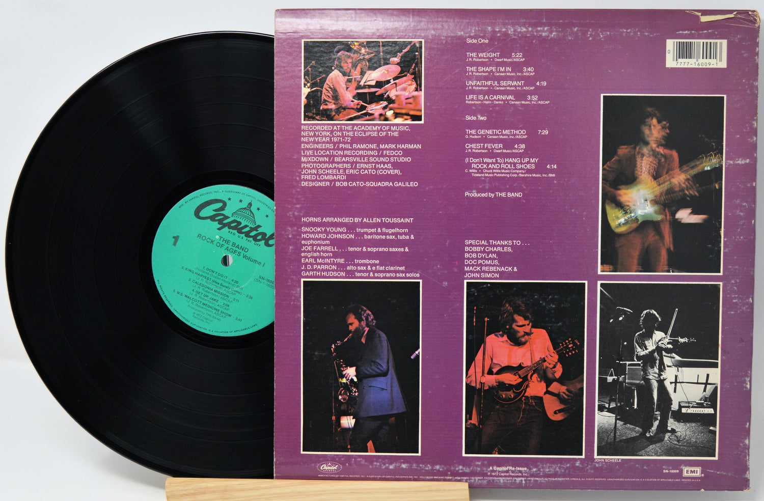 A vinyl record partially pulled from its back cover sleeve, showing the black record, a green center label, and the purple back cover with printed track listings and performer photos.