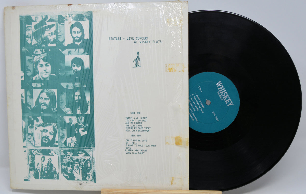Beatles 'Live Concert at Wacken' vinyl record LP with the outer sleeve on the left and the black record partially visible on the right. The sleeve features a teal-toned collage of band members on the left and printed track listing text on the right, all wrapped in clear plastic.