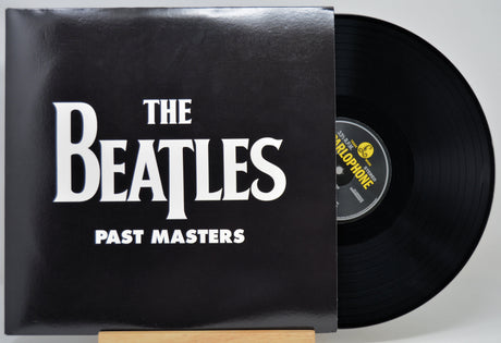 The Beatles 'Past Masters' vinyl record with the black album cover and part of the black record visible, photographed against a light gray background.