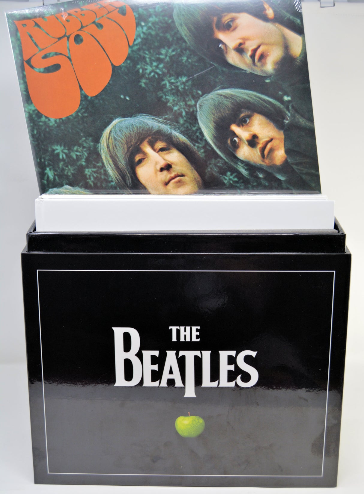 The Beatles vinyl record box set with the outer black box and a record sleeve leaning out on top, photographed against a plain light background.