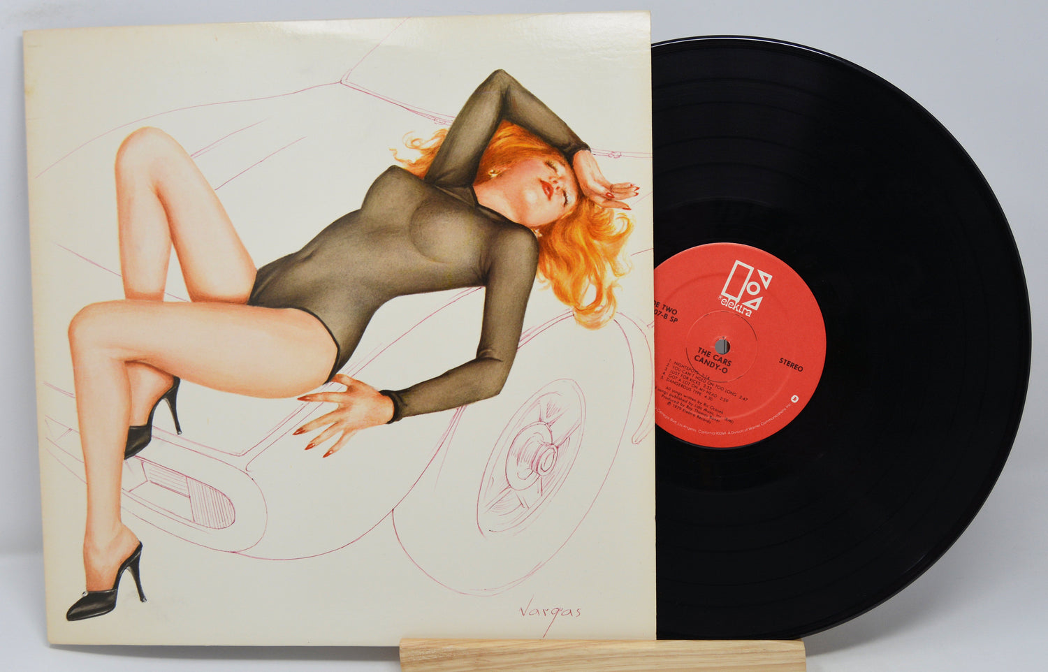 Used vinyl record of The Cars - Candy-O with the album cover showing a sketch of a sexy red headed woman lying across the hood of a car.