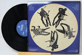 Vinyl record with a blue and beige cover featuring black silhouette art of a musician playing guitar.