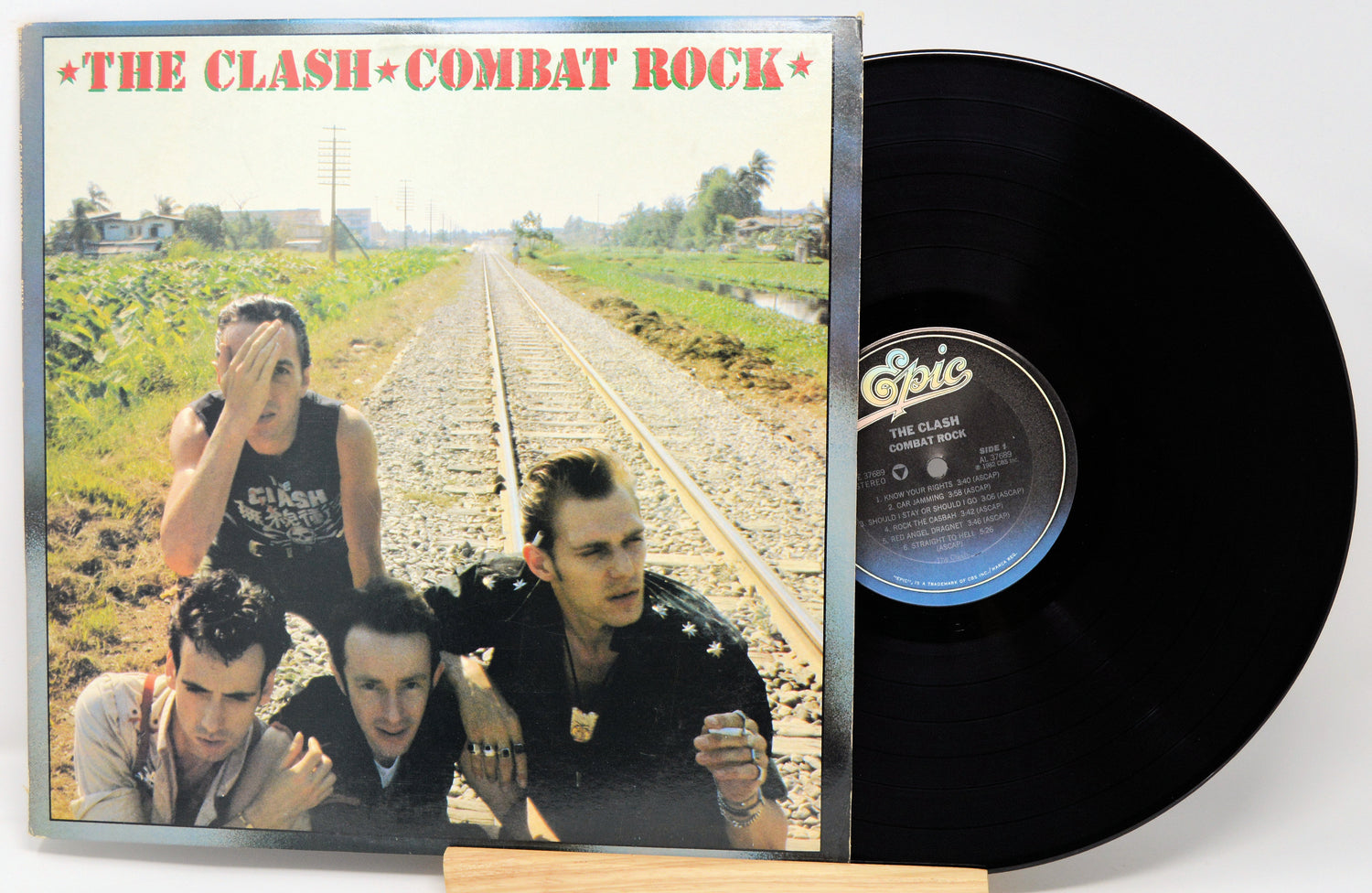 Vinyl record with 'The Clash - Combat Rock' album cover showing four band members on railway tracks.