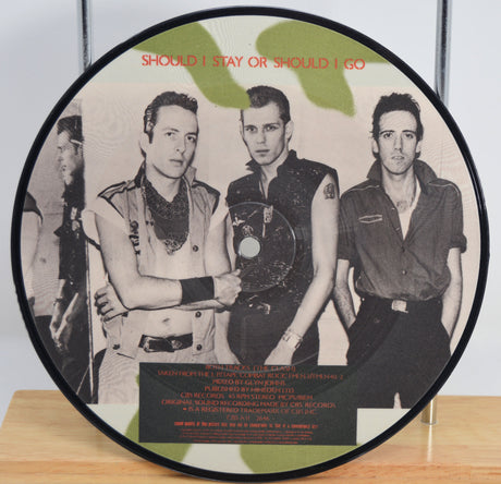 'The Clash' Picture disc with the band portrait and text 'Should I Stay or Should I Go' on a wooden surface.