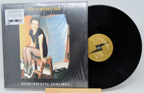 Front cover and vinyl record of The Cranberries Remembering Dolores 2LP showing Dolores O'Riordan seated and album sticker