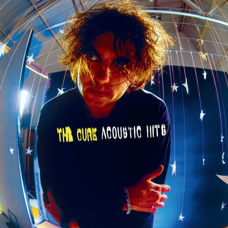 Person wearing a black sweatshirt with 'The Cure Acoustic Hits' text, surrounded by decorative lights.