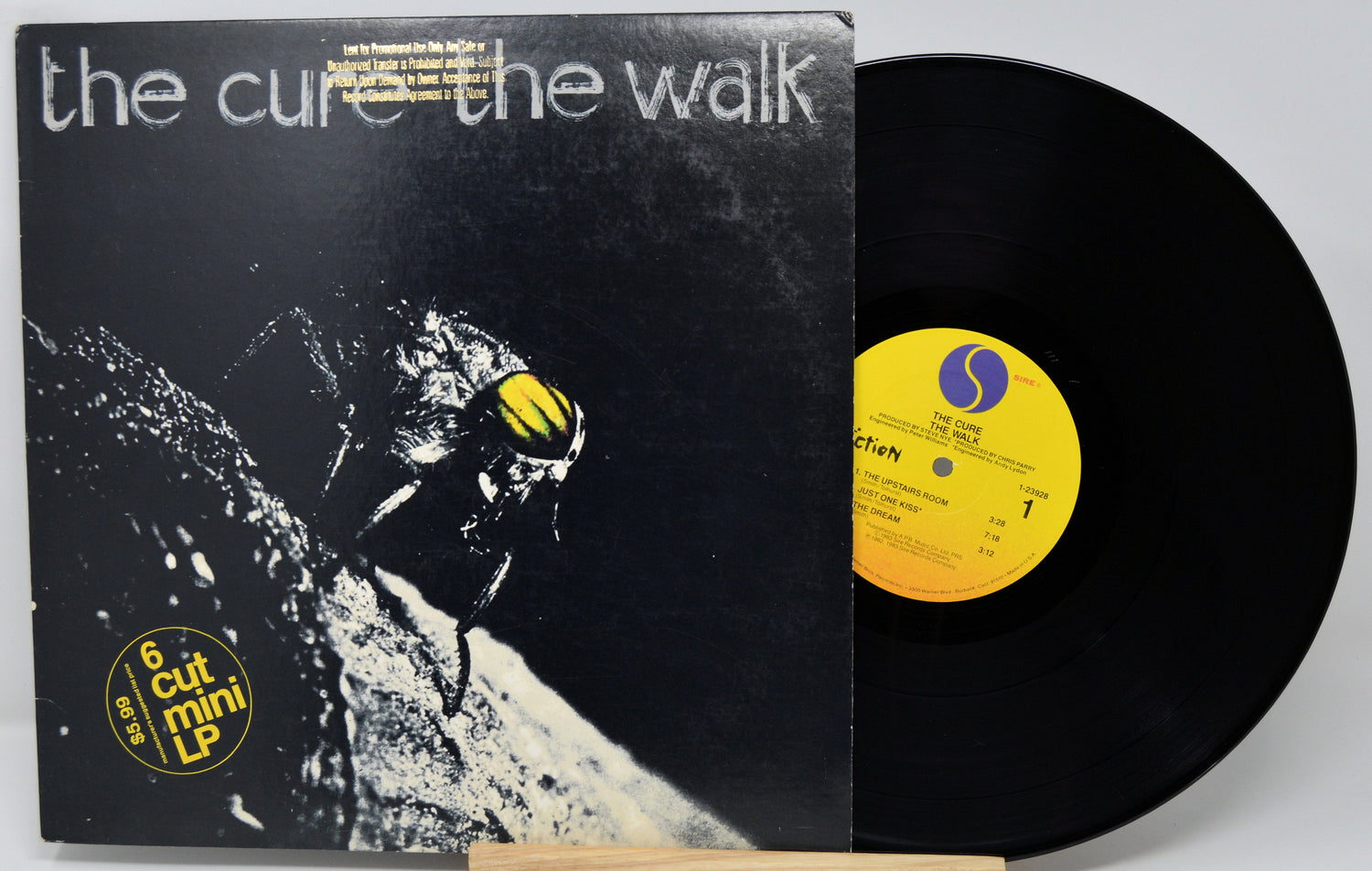 Vinyl record with cover featuring a bee and text 'the cure the walk' on a white background