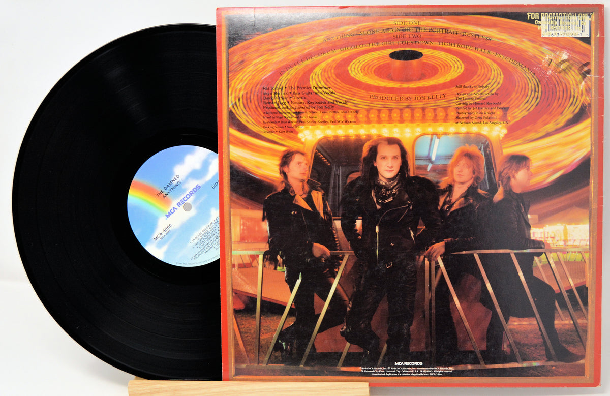 A vinyl record partially pulled from its album cover, showing the black record on the left and the printed cover art on the right. The cover features a bright orange circular light effect and three people standing in front of a vehicle, with the band name 'Metallica' visible on the label.