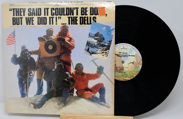 Vinyl record with cover featuring mountain climbers and text 'They said it couldn't be done, but we did it! The Delis'.