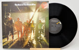 Vinyl record with cover featuring a band in front of a sunlit wall.