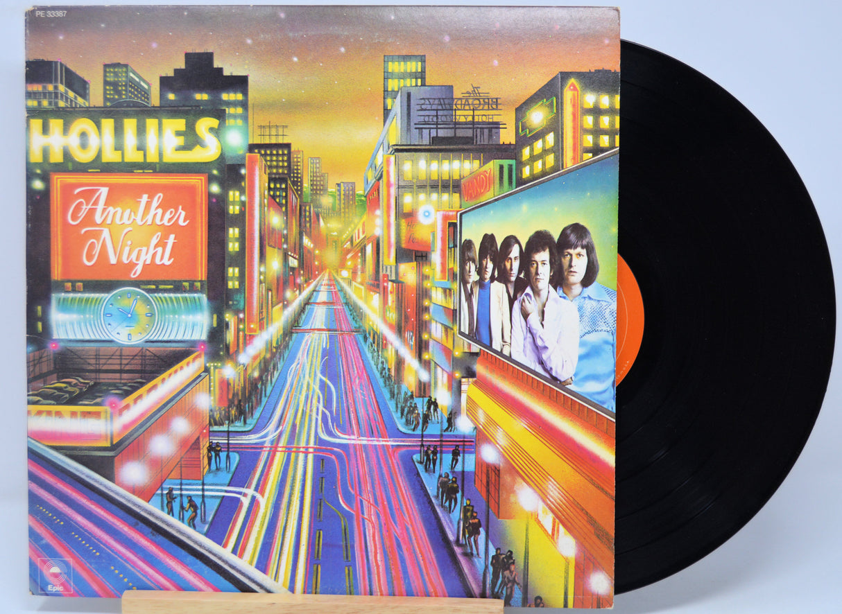 Vinyl record with a colorful cover featuring a cityscape and band members, titled 'Another Night' by The Hollies.
