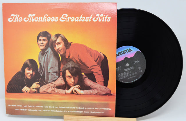 Vinyl record with 'The Monkees Greatest Hits' album cover showing four band members.