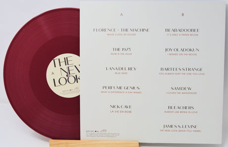 Vinyl record with maroon disc and white cover featuring album tracklist on a light gray background