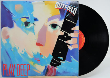 Vinyl record with a colorful cover featuring a stylized face and 'Outfield' branding.
