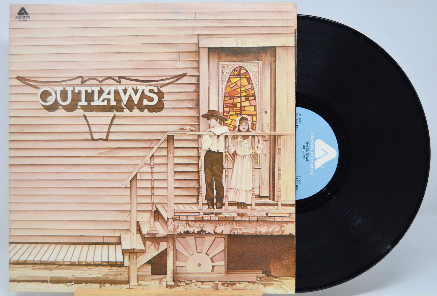 Vinyl record with 'Outlaws' album cover featuring a couple on a porch.