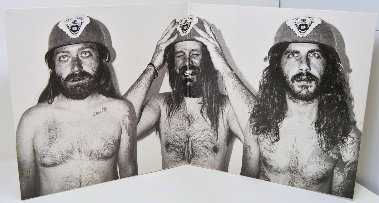 Black and white photo of three long-haired men wearing helmets with wolf emblem, inside vinyl gatefold