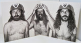 Black and white photo of three long-haired men wearing helmets with wolf emblem, inside vinyl gatefold