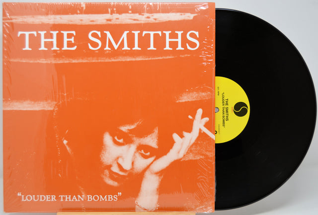 Vinyl record with 'The Smiths' 'Louder Than Bombs' album cover featuring an orange background and a face.