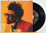 Vinyl record with a cover featuring The Weeknd wearing sunglasses and a red jacket, set against an orange and gray gradient background. Song - Blinding Lights