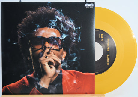 The Weekend Heartless variant #10 7 Inch Vinyl record with a black front cover featuring a person wearing sunglasses and a red jacket, and a yellow record inside.