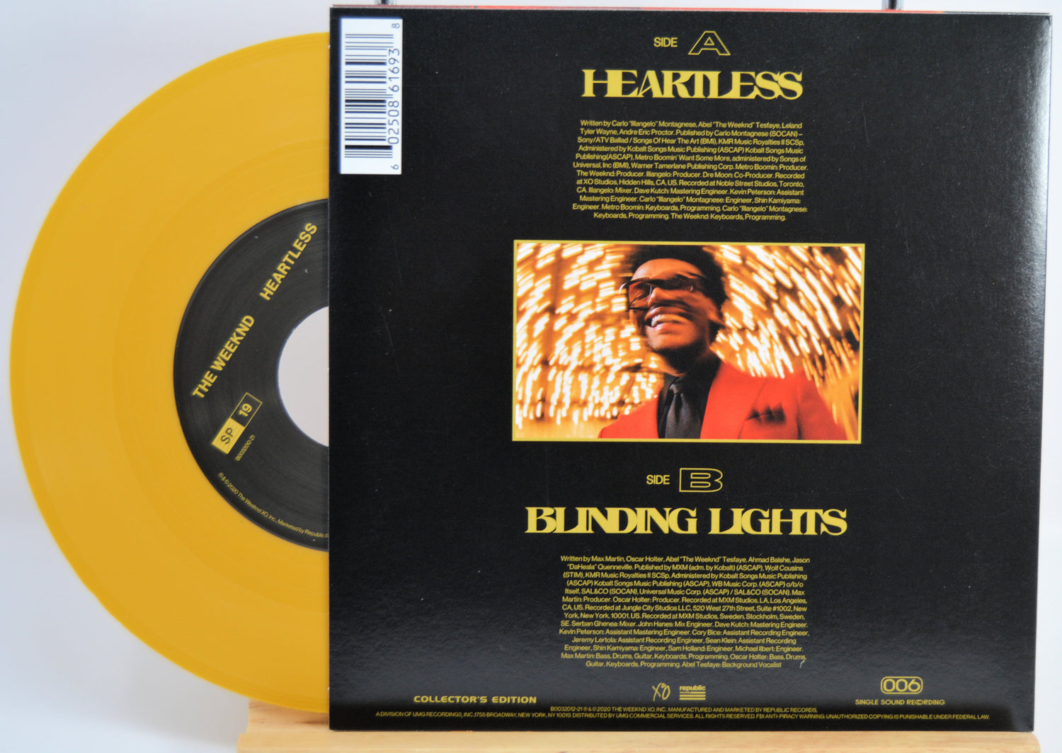The Weekend Heartless variant #7 7 Inch Vinyl record with a black back cover featuring a person wearing sunglasses and a red jacket, and a yellow record inside.