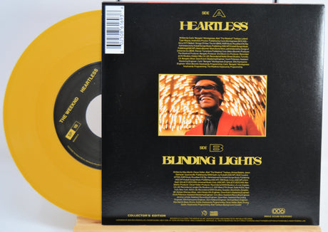 The Weekend Heartless variant #7 7 Inch Vinyl record with a black back cover featuring a person wearing sunglasses and a red jacket, and a yellow record inside.
