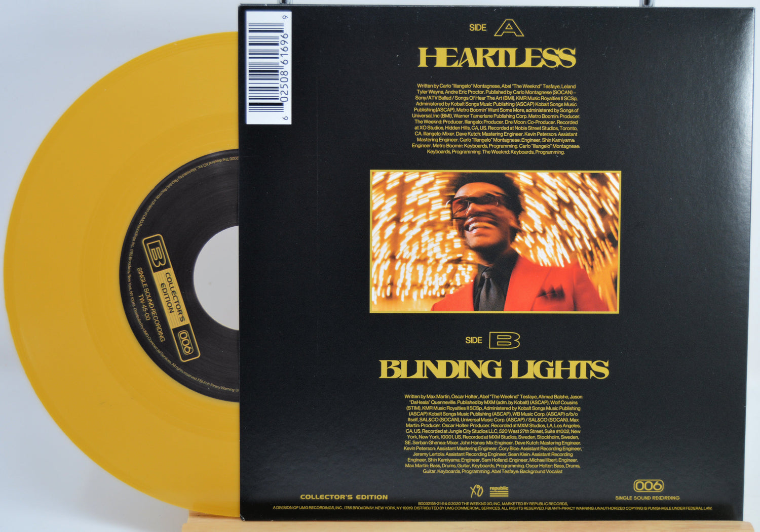 The Weekend Heartless variant #10 7 Inch Vinyl record with a black back cover featuring a person wearing sunglasses and a red jacket, and a yellow record inside.