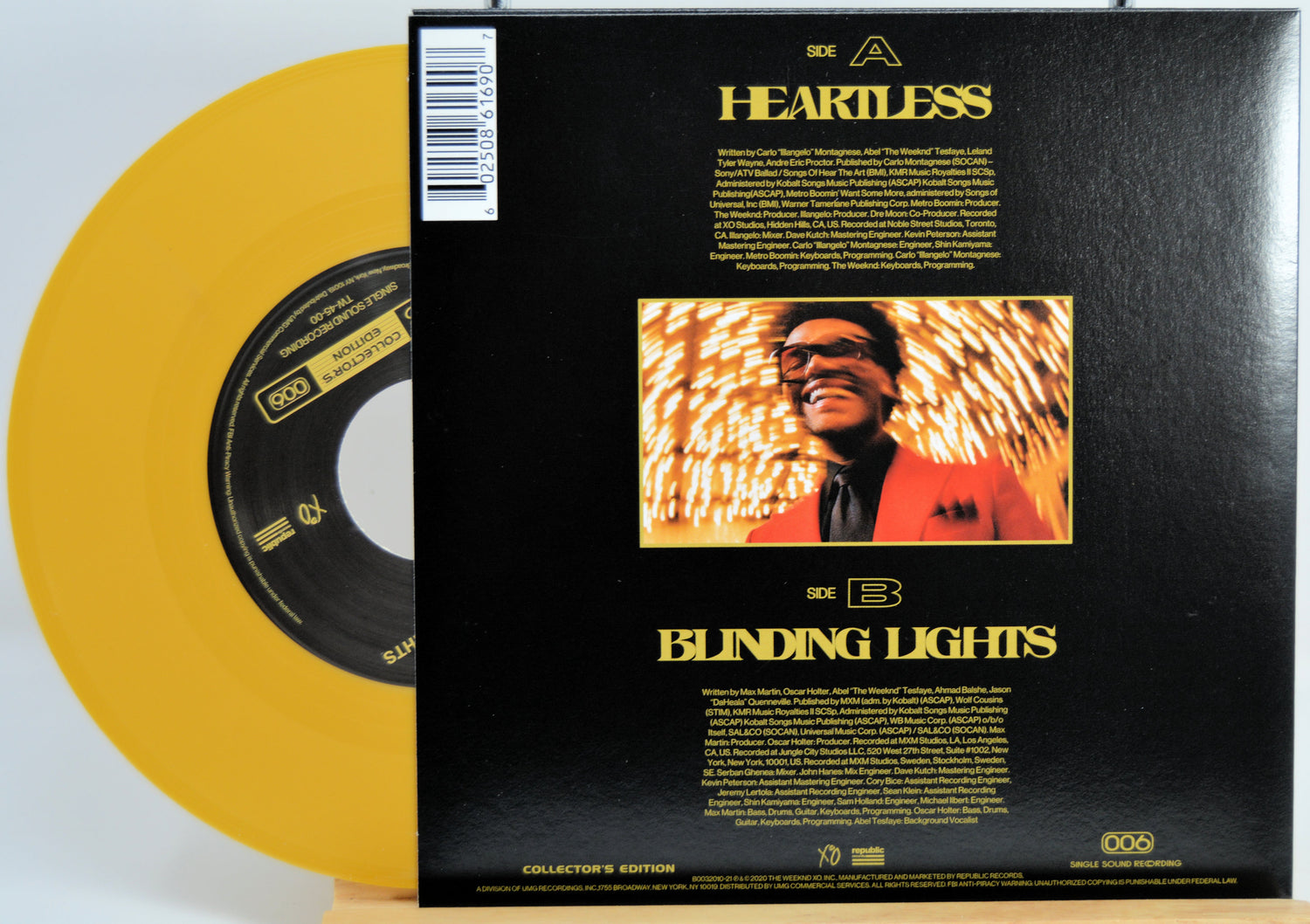 The Weekend Heartless variant #5 7 Inch Vinyl record with a black back cover featuring a person wearing sunglasses and a red jacket, and a yellow record inside.