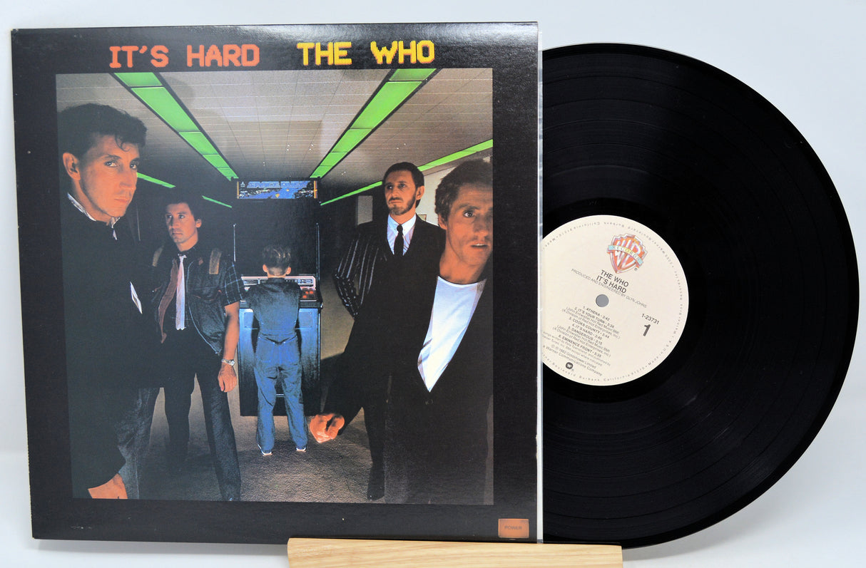 The image shows a vinyl record titled 'It's Hard' by The Who, with the album cover in the background featuring four members of the band.