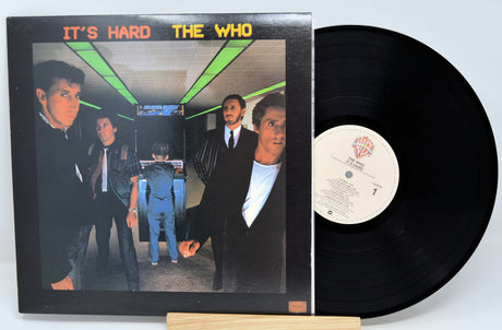 The image shows a vinyl record titled 'It's Hard' by The Who, with the album cover in the background featuring four members of the band.