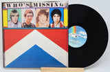 A vinyl record titled 'Who's Missing' by The Who, displayed in its sleeve with the band's name and a graphic design. The record itself is black, and there is a label with a barcode and text on the upper part of the sleeve.